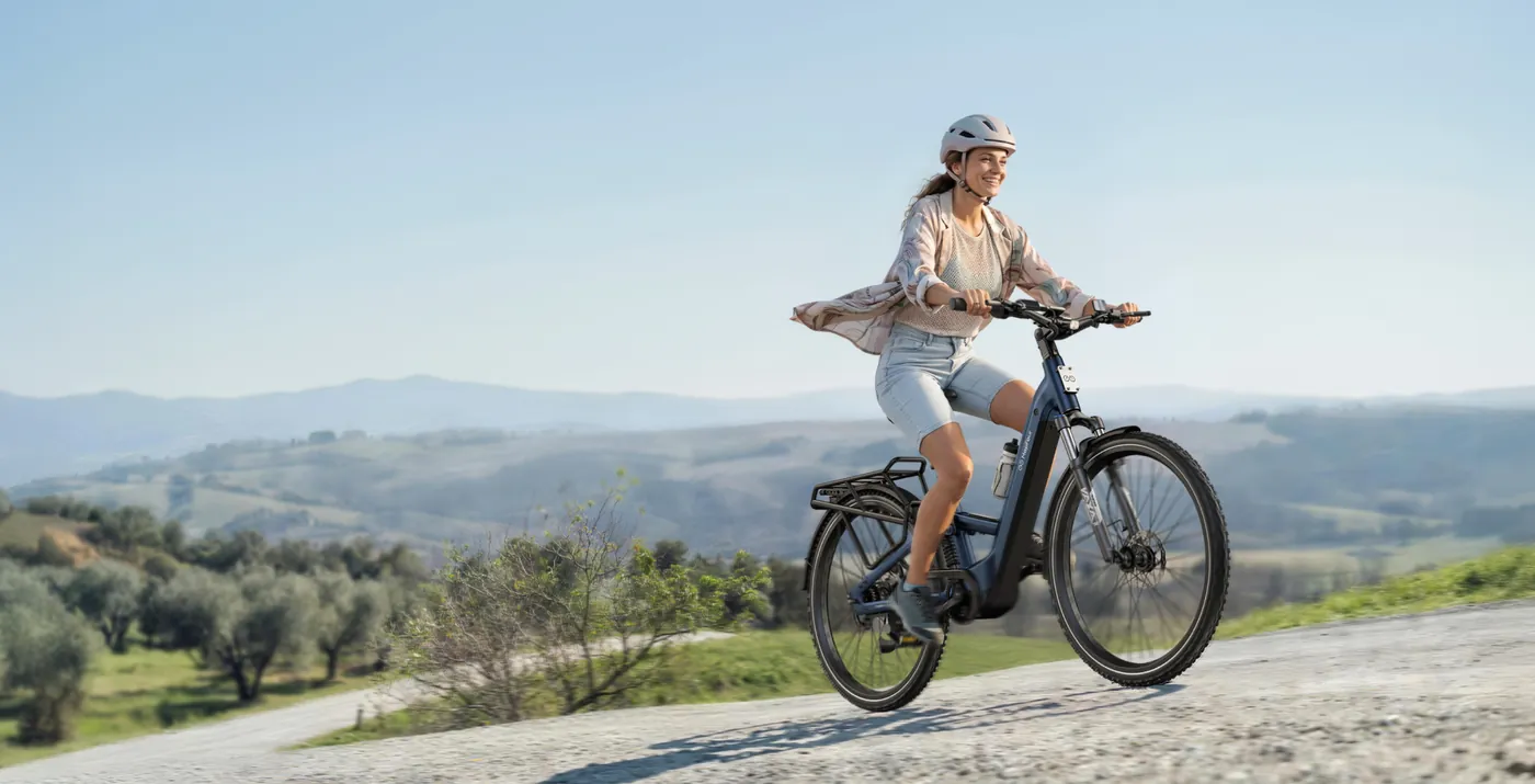Woman riding a MapFour Roam ST uphill on a gravel road